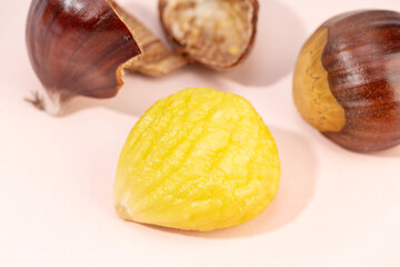 Peeled sweet chestnut on pink background. Castanea sativa