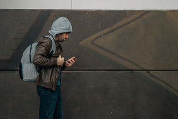 man walking in autumn or winter on the street with mobile phone