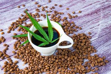 A cup of coffee cannabis with Marijuana leaves and coffee beans on wooden table.
