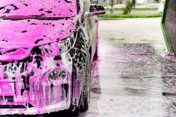 electric car at a self-service car wash. pink car wash. clean car. electric car cleaning. average...