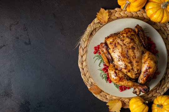 Baked chicken for Thanksgiving Day. Roasted chicken or turkey with herb rosemary and berry and pumpkins for Thanksgiving dinner on dark table. Festive table settings for Thanksgiving Day. Copy space