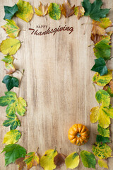 Naklejka na ściany i meble Happy Thanksgiving text with pumpkins and leaves on light wooden background