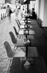 A row of tables in an outdoor cafe on the street.