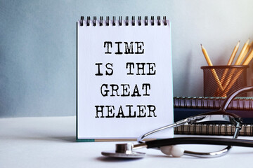 TIME IS THE GREAT HEALER - written on a notepad. Doctor's workplace. Work table with medical equipment and office supplies. Medical concept.