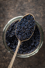 Black caviar in silver spoon on dark table.