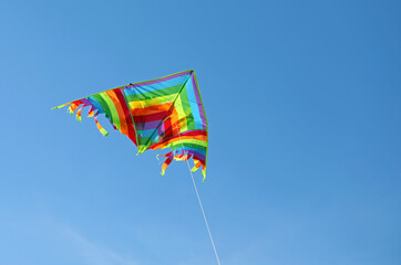 colorful kite flies in the blue sky attached to the string so as not to lose it