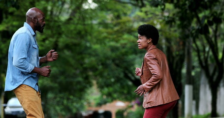 African couple dancing together outside in street