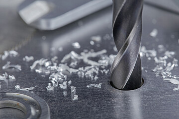 metal drill bit make holes in steel billet on industrial drilling machine with shavings. Metal work...