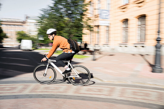 A blurry photo in motion. A cyclist in a helmet rides a bicycle to work in the city, eco-transport.