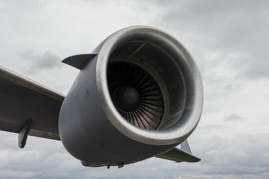 Detail of aircraft engine. Jet turbine on the aeroplane and plane wing. Cloudy sky. Bottom view and low angle.