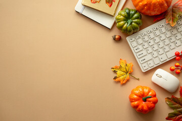 Autumn office workspace. Autumn flat lay background. Keyboard, laptop with autumn cloth and fall decorations - pumpkin, leaves and other.