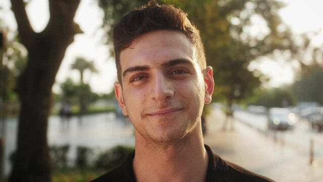 Close-up portrait of young handsome man Lebanese or Palestinian descent standing outdoors alone smiling looking at camera. Beautiful people, city lifestyle and urban youth concept.