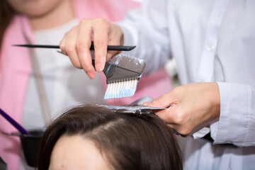 Hairdresser stylist takes care of girl's hair. Hair care procedures in a beauty salon. Hair...