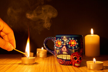  dia de los muertos or day of the dead concept. Hand with match lighting candle by mexican sugar...