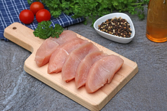 Rohe Putensteak auf einem K&uuml;chenbrett. 