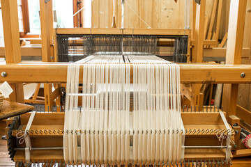 close up of weaving machine. A loom machine for clothing or woven label. Weaving machine for garment industry. Yarn thread lines on the weaving loom machine for clothing in textile factory.