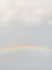 Photo of bright and colorful rainbow in the air. Cloudscape after rainfall.