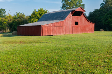 An old red barn in the summer hay field, in Tennessee.