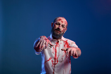 Portrait of man zombie with scratches and sinister wounds posing in front of camera, dangerous undead corpse with scary scars and creepy face in studio. Doomsday cruel monster devil.