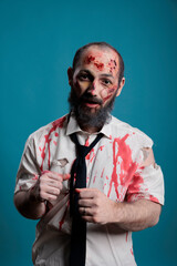Portrait of brain eating zombie in studio having bloody wounds and dirty scars, acting dangerous and deadly. Eerie apocalyptic monster looking evil and aggressive, crazy thriller devil.