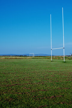 Field with tall goal posts for Irish National sports on green grass against clear blue sky. Rugby, hurling, camogie and Gaelic football training ground. Nobody. Popular sport in Ireland.