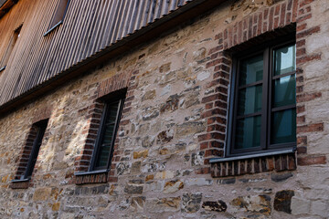 A row of windows in the wall of an old building made of broken stone