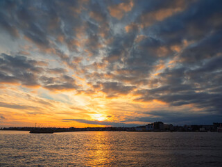 Dramatic sunset over Galway city and bay. Beautiful sky with warm and cool tones over city buildings silhouette. River Corrib and the Long walk area of the city.