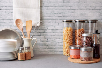 Assortment of grains, cereals and pasta in glass jars and kitchen utensils on wooden table