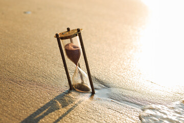 Antique sandglass lost in the sand on the beach. The sands of Time.