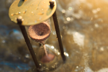 Antique hourglass lost in the water on the beach. The sands of Time.