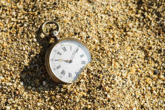 Antique pocket watch lost in the sand. Old watch buried in sand.