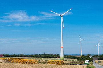 Yellow metal structures lying on the field in front of windmills.