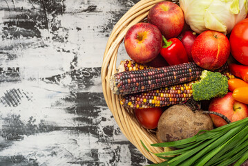 Wicker basket full of vegetables and fruits top view. Autumn and harvest time. Space for text.