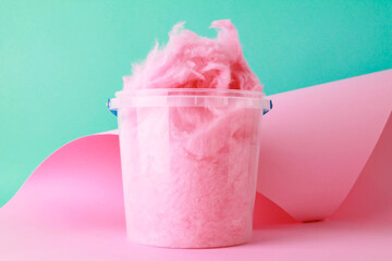 close up sweet fluffy pink color cotton candy in plastic basket package on pink green background....