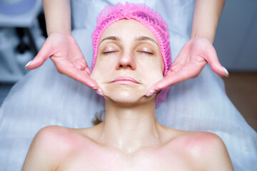 Attractive female at spa health club getting a facial massage. Beautician doing massage of face, neck and shoulders ofbeautiful young woman at luxury beauty salon