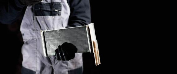 car radiator of the heater in the hands of the master on a dark background. The concept of...