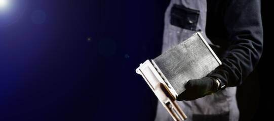 car radiator of the heater in the hands of the master on a dark background. The concept of...
