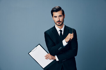 Portrait of a business man in a stylish suit smile with tie beautiful face on a blue isolated background with a tablet in his hands. Business concept young businessman startup copy place