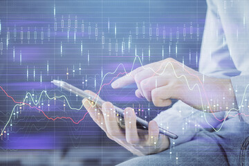 Fototapeta premium Double exposure of man's hands holding and using a digital device and forex graph drawing. Financial market concept.