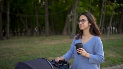 Obraz premium A young mother walks with her son in the park. A woman in glasses with a baby in the park. Closeup.