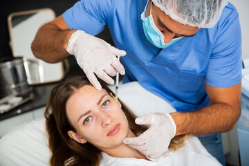 Portrait of young woman patient of beautician receiving rejuvenating facial injections
