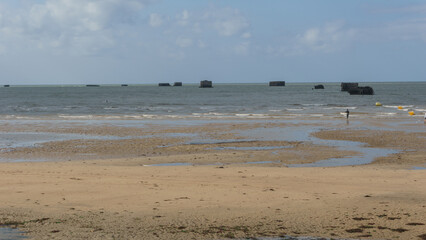 Fototapeta na wymiar The ruins of artificial port of Gold beach on sunny summer day in Asnelles, Normandy, France
