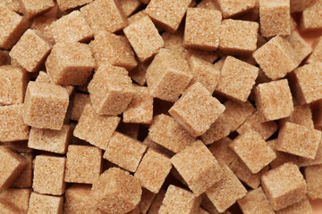 Brown sugar cubes as background, top view