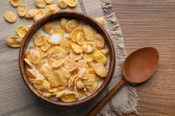 Tasty cornflakes with milk in bowl served on wooden table, flat lay