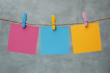 Wooden clothespins with colorful blank notepapers on twine against marble background. Space for text