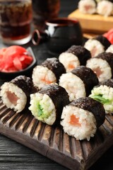 Tasty sushi rolls served on black wooden table, closeup