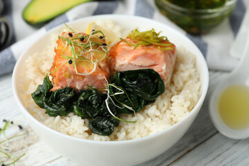 Tasty salmon with rice and spinach on white wooden table, closeup