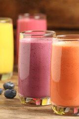 Glasses with different tasty smoothies on wooden table