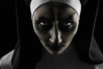 Portrait of scary devilish nun on black background, closeup. Halloween party look