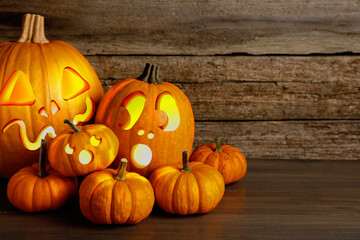 Spooky jack o`lanterns on wooden table, space for text. Halloween decor